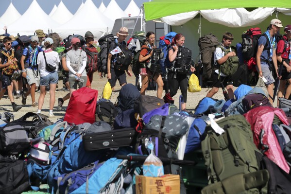 Attendees of the World Scout Jamboree leave a scout camping site in Buan, South Korea, Tuesday, Aug. 8, 2023. Buses began moving thousands of global Scouts from their campsite on South Korea's coast to inland venues Tuesday ahead of a tropical storm that is forecast to bring intense rains and strong winds to the peninsula within days. (Kim Myung-nyeon/Newsis via AP)