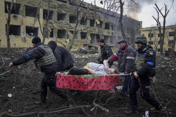 FILE - Ukrainian emergency employees and volunteers carry an injured pregnant woman from the maternity hospital that was damaged by shelling in Mariupol, Ukraine, Wednesday, March 9, 2022. A Russian attack has severely damaged the maternity hospital in the besieged port city of Mariupol, Ukrainian officials say. (AP Photo/Evgeniy Maloletka, File)
