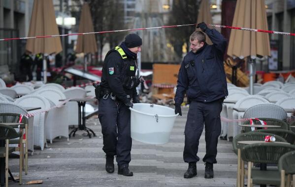 Police officers carry a plastic tub with rescued fish after a huge aquarium bursts in Berlin, Germany, Friday, Dec. 16, 2022. German police say a huge fish tank in the center of Berlin has burst, causing a wave of devastation in and around the Sea Life tourist attraction. (Soeren Stache/dpa via AP)