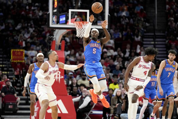 Oklahoma City Thunder guard Luguentz Dort (5) passes the ball as Houston Rockets forward Dillon Brooks, left, defends during the first half of an NBA basketball game Sunday, Feb. 25, 2024, in Houston. (AP Photo/Eric Christian Smith)