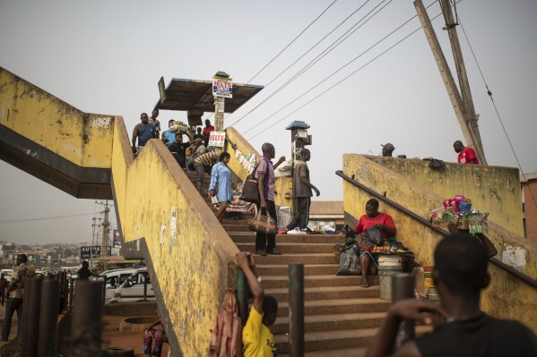 People cross a pedestrian bridge as street vendors sell their goods, in Anambra, Nigeria, Friday, Feb. 24, 2023. Nigerian voters are heading to the polls Saturday to select a new president following the second and final term of incumbent President Muhammadu Buhari. (AP Photo/Mosa'ab Elshamy)