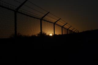 The sun sets behind a border fence separating Del Rio, Texas, and Ciudad Acuna, Mexico, Thursday, Sept. 23, 2021. Each year, the border communities that sit across the Rio Grande from one another come together to celebrate the Fiesta de la Amistad. (AP Photo/Fernando Llano)