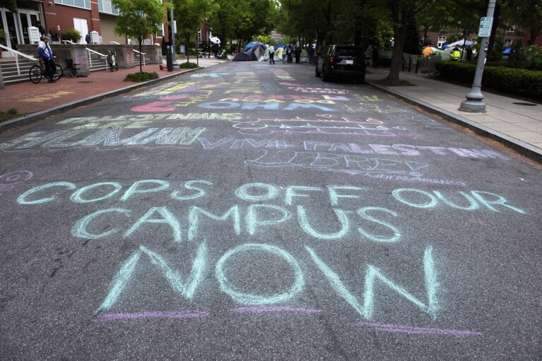 A chalk statement is seen on the road leading to the George Washington University Yard as students protest the Israel-Hamas war, in Washington, Saturday, April 27, 2024. (AP Photo/Cliff Owen)