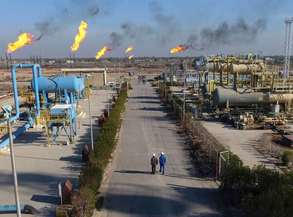 
              FILE - in this Thursday, Jan. 12, 2017 laborers walk down a path in the Nihran Bin Omar field north of Basra, Iraq. Emerging from a grueling war with the Islamic State group for more than three years, Iraq plans to open more of its untapped oil and gas resources to foreign developers to boost reserves and to increase sorely needed revenues for post-war construction by offering rights to explore and develop hydrocarbon-rich areas. (AP Photo/ Nabil al-Jurani, File)
            