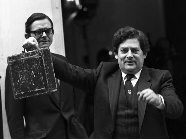 In this March 13, 1984 file photo, Nigel Lawson holds the budget box leaving 11 Downing Street in London to present his budget to the House of Commons. Lawson, the tax-cutting UK Treasury chief under the late Margaret Thatcher and a lion of Conservative politics in the late 20th century has died. He was 91. (PA via AP)