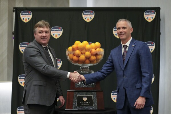 Georgia head coach Kirby Smart, left, and Florida State head coach Mike Norvell pose for photographers during a press conference a day ahead of the Orange Bowl NCAA college football game, in Dania Beach, Friday, Dec. 29, 2023. Georgia and Florida State will play in the Orange Bowl Saturday at Hard Rock Stadium in Miami Gardens. (AP Photo/Rebecca Blackwell)