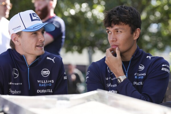 Williams driver Logan Sargeant, left, of the US and teammate Alexander Albon of Thailand react as they sit outside their team garage ahead of the Australian Formula One Grand Prix at Albert Park, Melbourne, Australia, Thursday, March 21, 2024. (AP Photo/Asanka Brendon Ratnayake)