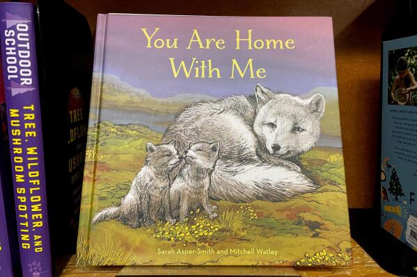 The children's book "You Are Home With Me," illustrated by Mitchell Thomas Watley, is shown at a bookstore in Portland, Ore. in this April 5, 2023 photo. Publisher Sasquatch books, owned by Penguin Random House, said Wednesday, April 5, 2023, it has ended its publishing relationship with Watley after he was arrested on allegations of leaving violent, transphobic notes in stores around Juneau, Alaska. Watley told police he was motivated by fear following a deadly school shooting in Nashville that sparked online backlash about the shooter's gender identity, court records show. (AP Photo/Claire Rush)