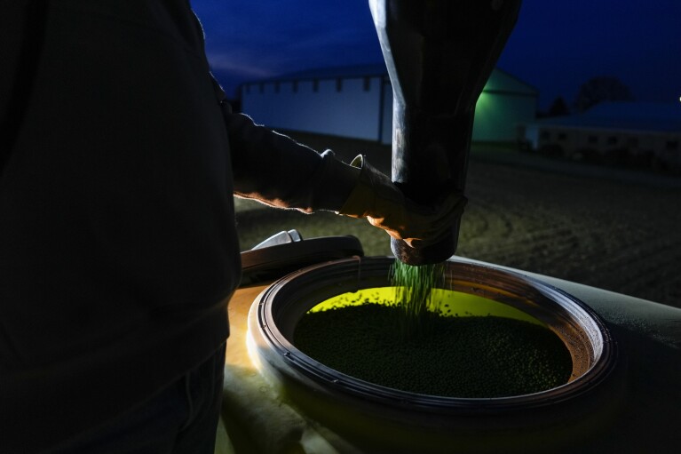 Mark Woodruff loads more soybean seeds into a planter, Monday, April 22, 2024, in Sabina, Ohio. When farmers have to wait for fields to dry out, already long planting days can become endurance tests that stretch into the night. (AP Photo/Joshua A. Bickel)