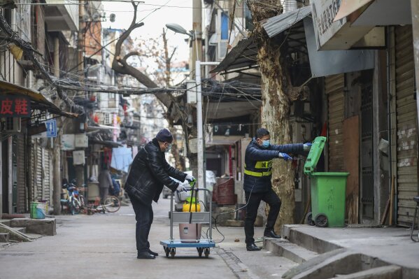 Government workers spray disinfectant on a garbage can in Wuhan in central China's Hubei Province, Tuesday, Jan. 28, 2020. Hong Kong's leader announced Tuesday that all rail links to mainland China will be cut starting Friday as fears grow about the spread of a new virus. (Chinatopix via AP)