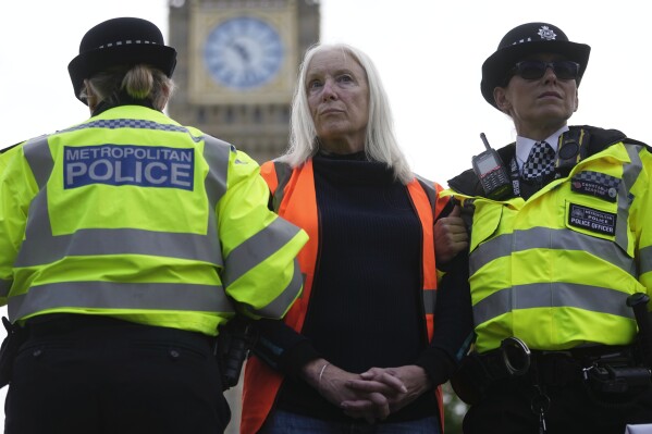 FILE- An activist from the group Just Stop Oil is arrested by police officers as they slow the traffic, marching on a road, in London, on Oct. 30, 2023. Britain's High Court ruled Tuesday, May 21, 2024, that new regulations that gave U.K. police more powers to intervene in protests were unlawful. Campaign group Liberty brought legal action against the British government over a law passed last year that lowered the threshold for what is considered “serious disruption” to community life caused by a protest. (AP Photo/Kin Cheung, File)