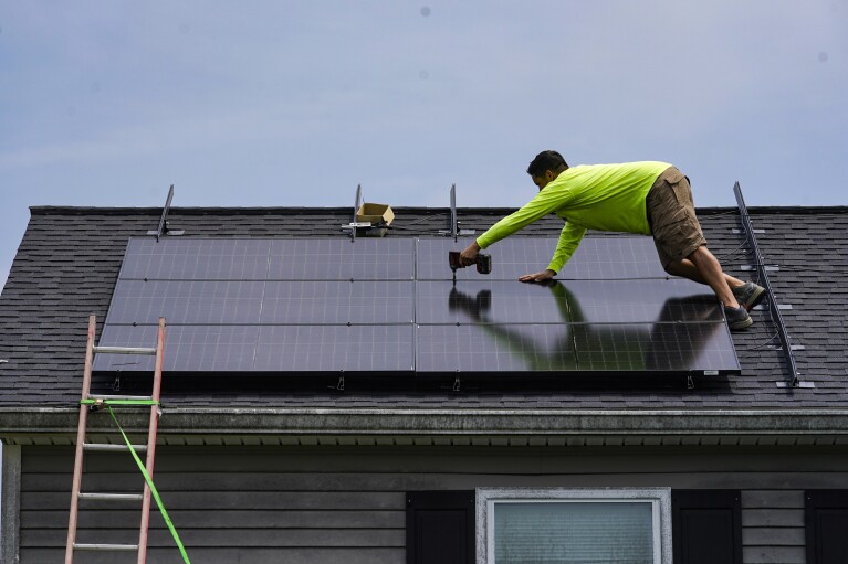 Nicholas Hartnett, owner of Pure Power Solar, secures solar panels on a rooftop in Frankfort, Kentucky, Monday, July 17, 2023. (AP Photo/Michael Conroy)