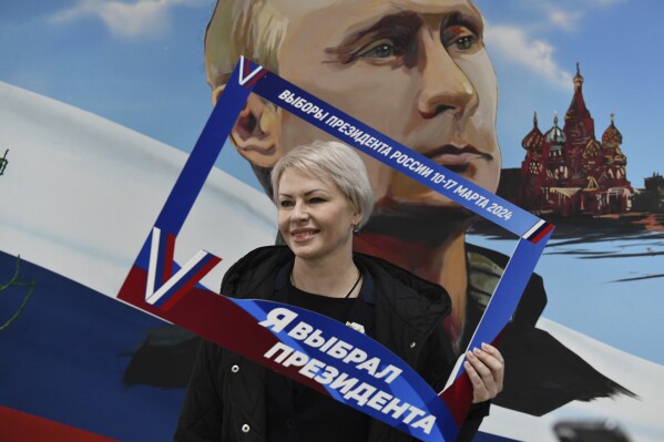 A woman poses with a frame with the words reading "I've have chosen the president" after voting at a polling station during a presidential election in Donetsk, Russian-controlled Donetsk region of eastern Ukraine, on Friday, March 15, 2024. People in Moscow-controlled Ukrainian regions voted in Russia's presidential election, which was all but certain to extend President Vladimir Putin's rule after he clamped down on dissent. (AP Photo)