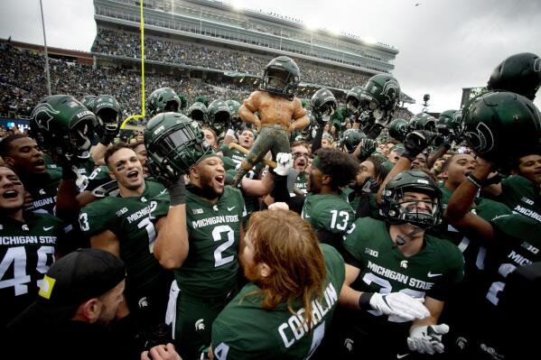 Michigan State players celebrate with the Paul Bunyan trophy defeating Michigan in an NCAA college football game, Saturday, Oct. 30, 2021, in East Lansing, Mich. Michigan State won 37-33. (Jake May/The Flint Journal via AP)
