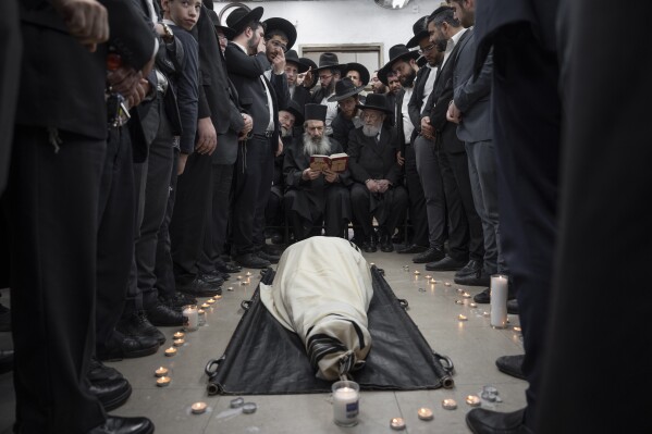Ultra-Orthodox Jews mourn over the body of Rabbi Shimon Baadani during his funeral, in Bnei Brak, Israel, Wednesday, Jan. 11, 2023. (AP Photo/Oded Balilty)