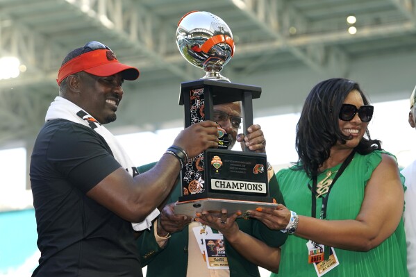 Florida A&M head coach Willie Simmons, left, holds the trophy with Florida A&M president Dr. Larry Robinson, center, and athletic director Tiffani-Dawn Sykes, right, after defeating Jackson State in the Orange Blossom Classic NCAA college football game, Sunday, Sept. 3, 2023, in Miami Gardens, Fla. (AP Photo/Lynne Sladky)