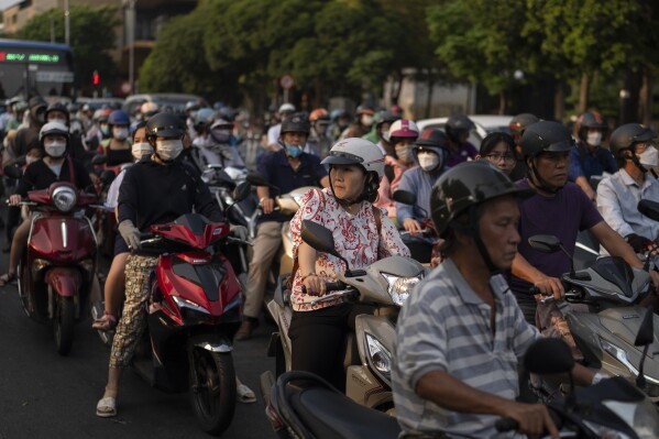 Scooter commuters wait for a traffic light to change at an intersection in Ho Chi Minh City, Vietnam, Jan. 12, 2024. (AP Photo/Jae C. Hong)