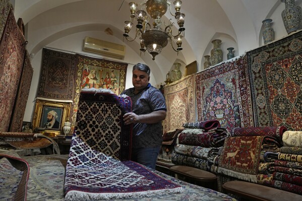 Iranian carpet shop owner Ali Faez works at his shop at the traditional bazaar of the city of Kashan, about 152 miles (245 km) south of the capital Tehran, Iran, Tuesday, April 30, 2024. (AP Photo/Vahid Salemi)