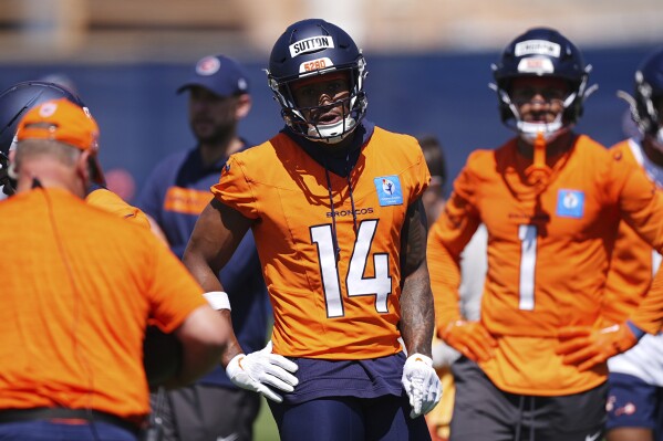 Denver Broncos wide receiver Courtland Sutton, center, and tight end Evan Engram, right, get direction from a coach as players take part in drills during an NFL football team practice Thursday, June 5, 2025, in Centennial, Colo. (AP Photo/David Zalubowski)