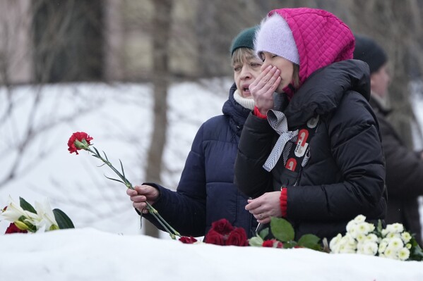 Vrouwen reageren om hulde te brengen aan Alexei Navalny bij het monument, een groot rotsblok op de Solovetski-eilanden waar het eerste kamp van het politieke gevangenissysteem van de Goelag werd gevestigd, vlakbij de historische Federale Veiligheidsdienst (FSB, opvolger van de Sovjet-KGB).  gebouw in Moskou, Rusland, zaterdag 24 februari 2024.  Navalny, 47 jaar oud, Ruslands populairste oppositiepoliticus, stierf onverwachts in een strafkolonie op 16 februari, wat honderden Russen in het hele land ertoe aanzette om naar overhaaste herdenkingen te stromen.  Met bloemen en kaarsen.  (AP Foto/Alexander Zemlianichenko)