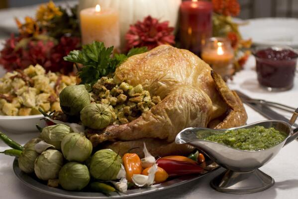 FILE - A grill-roasted brined turkey is presented on a table in Concord, N.H. Turkey is the center of most Thanksgiving meals, but it’s important to handle raw poultry properly to avoid spreading bacteria that can send your guests home with an unwanted side of food poisoning.  (AP Photo/Larry Crowe, File)