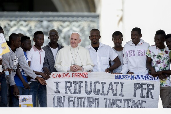 Pope Francis poses for a photo with a group of refugees he invited to join him on the steps of St. Peter's Basilica and holding a banner reading: "The refugees for future together" during the general audience in St. Peter's Square at the Vatican, Wednesday, June 22, 2016. Pope Francis embarks on a 2-day visit to the French port city of Marseille to join Catholic bishops from the Mediterranean region on discussions that will largely focus on migration. The visit comes amid a new influx of migrants across Europe. (AP Photo/Fabio Frustaci, File)