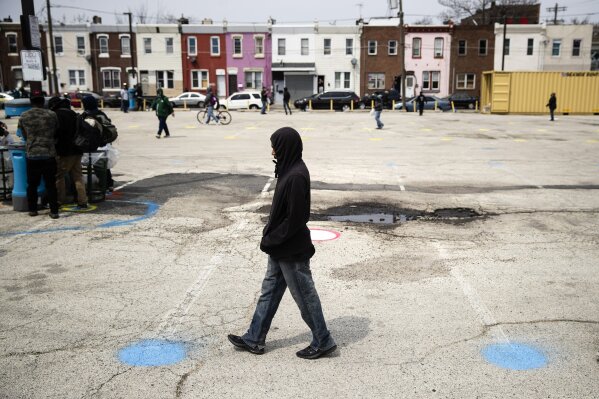 FILE - In this April 17, 2020, file photo a person moves between painted circles as he advances in line to wash his hands and receive food during the coronavirus outbreak as part of a new initiative called Step Up to the Plate in the Kensington neighborhood of Philadelphia. The program aims to help those with food insecurity and is a partnership of Broad Street Ministry, Prevention Point Philadelphia, and Project HOME, with the City of Philadelphia. (AP Photo/Matt Rourke, File)
