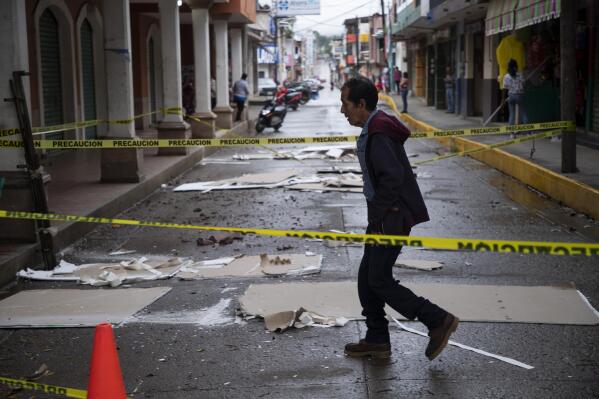 A resident walks through a street cordoned off amid debris from the previous day's earthquake in Coalcoman, Michoacan state, Mexico, Tuesday, Sept. 20, 2022. The magnitude 7.6 earthquake shook Mexico’s central Pacific coast on Monday, killing at least one person. (AP Photo/Armando Solis)