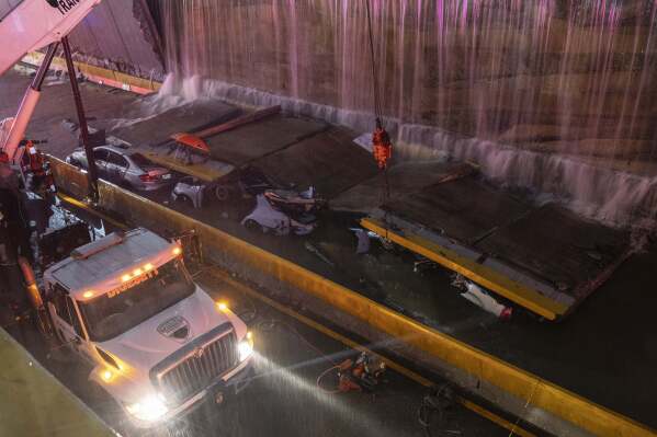 Rescue teams work at the place where a wall collapsed at the entrance of a tunnel in Santo Domingo, Dominican Republic, Saturday, Nov. 18, 2023. According to Civil Defense at least 9 people were killed when the wall fell down due to heavy rains. ( AP Photo/Eddy Vittini)