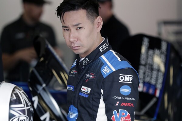 FILE - Kamui Kobayashi, of Japan, walks by his car in his garage before a practice session during testing for the upcoming Rolex 24 hour auto race at Daytona International Speedway, Jan. 3, 2020, in Daytona Beach, Fla. The NASCAR Cup Series race at Circuit of the Americas, Sunday, March 24, 2024, will be first of five on road or street courses this season and Kobayashi will be competing for 23XI Racing. (AP Photo/John Raoux, File)