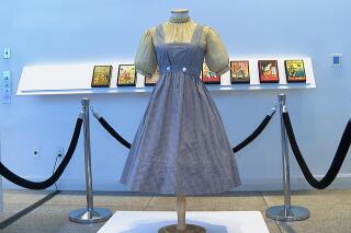 FILE - A blue and white checked gingham dress, worn by Judy Garland in the "Wizard of Oz," hangs on display, Monday, April 25, 2022, at Bonhams in New York.  A judge has blocked the planned auction of the dress, scheduled in Los Angeles on Tuesday, May 24 put up for sale by Catholic University of America after being rediscovered there in a shoebox during a renovation. Auctioneer Bonhams listed a presale estimate of $800,000 to $1.2 million for the dress before it was withdrawn. (AP Photo/Katie Vasquez)