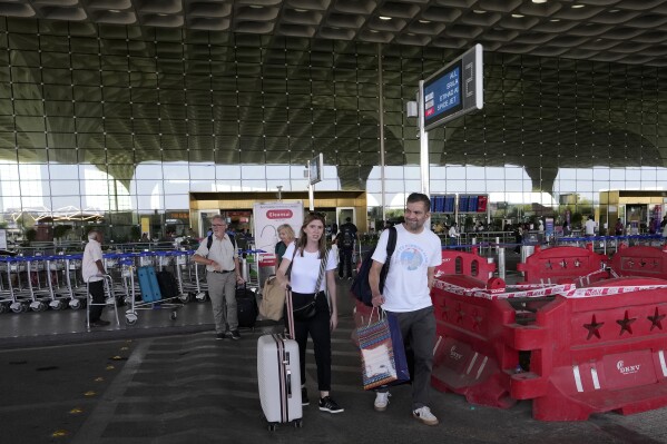 Travelers exit Chhatrapati Shivaji Maharaj International Airport after a fire at Heathrow Airport forced its closure, leading to numerous flight cancellations, in Mumbai, India, Friday, March 21, 2025. (AP Photo/Rajanish Kakade)