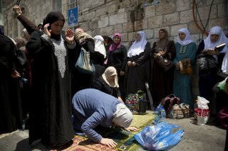 
              Palestinian women pray at the Lion's Gate following an appeal from clerics to pray in the streets instead of the Al Aqsa Mosque compound, in Jerusalem's Old City, Tuesday, July 25, 2017. Dozens of Muslims have prayed in the street outside a major Jerusalem shrine, heeding a call by clerics not to enter the site until a dispute with Israel over security arrangements is settled. This comes after Israel removed metal detectors earlier on Tuesday. (AP Photo/Oded Balilty)
            