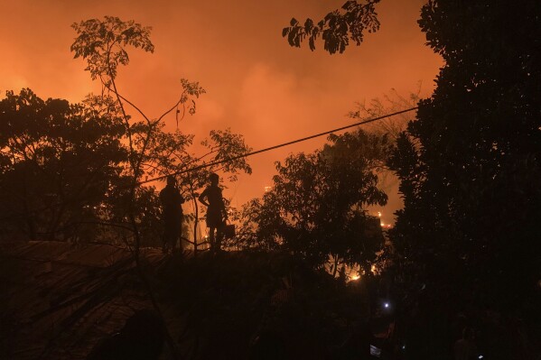 People watch a fire in a Rohingya refugee camp at Kutupalong in Cox's Bazar district, Bangladesh, early Sunday, Jan. 7, 2024. (AP Photo/ Shafiqur Rahman)