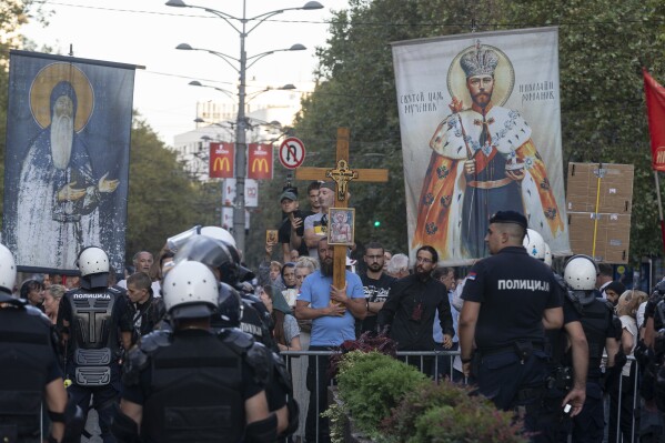 Anti-gay protesters hold crosses and religious banners amid heavy police presence and during a Pride march in Belgrade, Serbia, Saturday, Sept. 9, 2023. Hundreds of Pride activists gathered in the Serbian capital Saturday amid heavy police presence and anti-gay messages sent by the country's conservative leadership and far rights groups. (AP Photo/Marko Drobnjakovic)