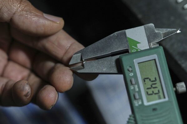 A diamond trader measures a diamond using a vernier caliper in Surat, India, on April 14, 2025. (AP Photo/Ajit Solanki)