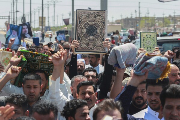 Supporters of the Shiite cleric Muqtada al-Sadr raise the Quran, the Muslim holy book, in response to the burning of a copy of the Quran in Sweden, during open-air Friday prayers in Basra, Iraq, Friday, June 30, 2023. (AP Photo/ Nabil al-Jurani)