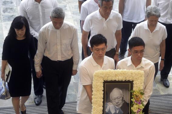 FILE - The family members of the late Lee Kuan Yew, Lee Hsien Yang, second left, his wife Lee Suet Fern, left, and Lee Hsien Loong, third left, arrive with his portrait at the state funeral at the University Cultural Center in Singapore on March 29, 2015. The brother of Singapore's prime minister is accusing government authorities of persecuting his family after it emerged that he and his wife were under official investigation. Lee Hsien Yang has long been at odds with his brother, Prime Minister Lee Hsien Loong, over the will of their late father — Singapore's first prime minister, Lee Kuan Yew. (AP Photo/Joseph Nair, File)