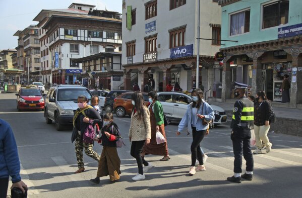 Bhutanese people wearing face masks as precaution against coronavirus cross a street in Thimpu, Bhutan, Monday, April 12, 2021. The tiny Himalayan kingdom wedged between India and China has vaccinated nearly 93% of its adult population since March 27. Overall, the country has vaccinated 62% of its 800,000 people. (AP Photo)