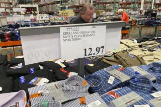 A sign displays the price for shirts as a shopper peruses the offerings at a Costco warehouse in this photograph taken Thursday, June 17, 2021, in Lone Tree, Colo.  Growth in U.S. consumer spending slowed in July to a modest increase of 0.3% while inflation over the past 12 months rose to the fastest pace in three decades.  (AP Photo/David Zalubowski)
