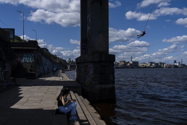 FILE - A bungee jumper hangs on a cord over the Dnieper River after jumping from the Park Bridge in Kyiv, Ukraine, Friday, July 28, 2023. (AP Photo/Jae C. Hong, File)