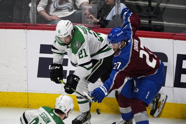 Dallas Stars left wing Jason Robertson, left, flips the puck past Colorado Avalanche left wing Jonathan Drouin in the third period of Game 4 of an NHL hockey Stanley Cup playoff series, Monday, May 13, 2024, in Denver. (AP Photo/David Zalubowski)