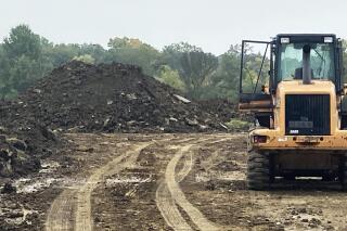 Soil is piled and prepared to be hauled from Rouge Park, Wednesday, Oct. 6, 2021, in Detroit, as part of a storm water retention project to reduce flooding on surrounding streets and the basements of home. Rainwater runoff would be directed into large retention basins in the park before being discharged into the nearby Rouge River. (AP Photo/Corey Williams)