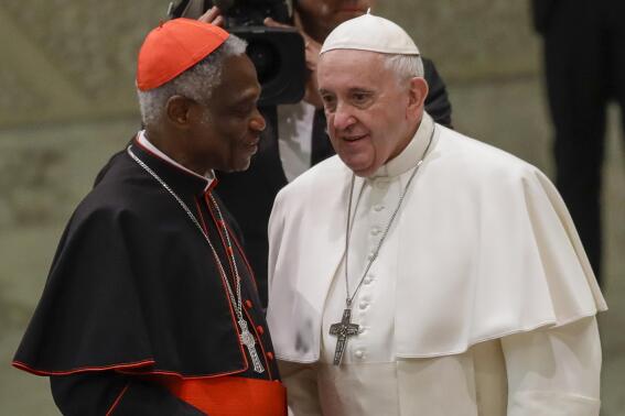 FILE  - Pope Francis talks with Cardinal Peter Kodwo Appiah Turkson during his weekly general audience, in Paul VI Hall at the Vatican, Wednesday, Jan. 15, 2020. Pope Francis on Thursday, Dec. 23, 2021 removed the head of the Vatican office that handles the high-priority issues of migration, environment and COVID-19 and put a trusted cardinal and one of the Holy See’s most influential nuns at the helm instead, albeit temporarily.
The Vatican said Francis thanked Cardinal Peter Turkson for his service, but had decided on new leadership after an initial five-year term and following the results of an internal investigation.  (AP Photo/Alessandra Tarantino, File)