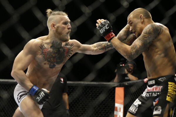 FILE - In this Sept. 27, 2014, file photo, Conor McGregor, left, and Dustin Poirier, exchange hits during their mixed martial arts bout in Las Vegas. UFC President Dana White confirmed to The Associated Press on Thursday, Nov. 19,2020, that McGregor has officially signed an agreement for a probable 155-pound fight with Poirier, ending McGregor's latest retirement from mixed martial arts. (AP Photo/John Locher, File)