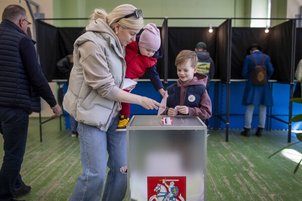 A woman with children casts a ballot at a polling station during the first round of voting in presidential elections in Vilnius, Lithuania, Sunday, May 12, 2024. (Ǻ Photo/Mindaugas Kulbis)