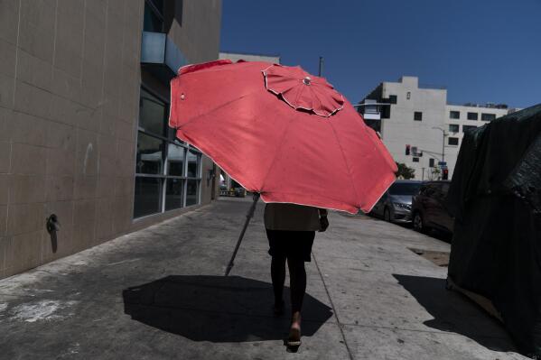 A woman walks with a beach umbrella in Los Angeles, Wednesday, Aug. 31, 2022. Excessive-heat warnings expanded to all of Southern California and northward into the Central Valley on Wednesday, and were predicted to spread into Northern California later in the week. (AP Photo/Jae C. Hong)