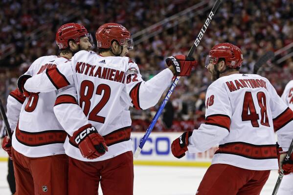 Carolina Hurricanes defenseman Brent Burns is congratulated by Jesperi Kotkaniemi (82) and Jordan Martinook (48) after scoring a goal against the New Jersey Devils during the second period of Game 4 of an NHL hockey Stanley Cup second-round playoff series Tuesday, May 9, 2023, in Newark, N.J. (AP Photo/Adam Hunger)