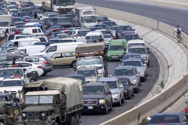 A general view of a petrol station on the main highway that link the Capital Beirut to south Lebanon as a man holds a gallon of fuel, right, while cars come from every direction to try and fill their tanks with gasoline, in the coastal town of Jiyeh, south of Beirut, Lebanon, Friday, Sept. 3, 2021.  Lebanon is mired in a devastating economic and financial crisis, the worst in its modern history. A result of this has been crippling power cuts and severe shortages in gasoline and diesel that have been blamed on smuggling, hoarding and the cash-strapped government’s inability to secure deliveries of oil products. (AP Photo/ Hassan Ammar)