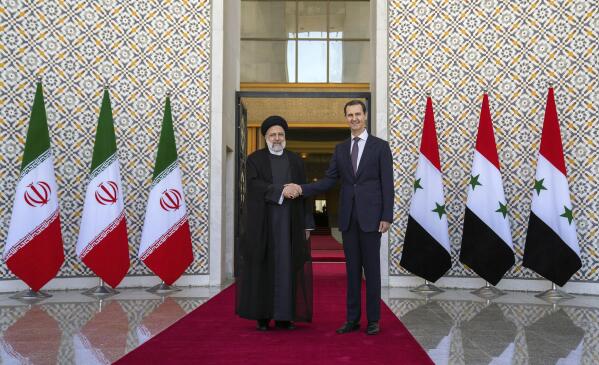 In this photo released by the official Facebook page of the Syrian Presidency, Syrian President Bashar Assad, right, shakes hands with Iranian President Ebrahim Raisi in Damascus, Syria, Wednesday, May 3, 2023. Iranian President Raisi Wednesday met Syrian President Assad in Damascus in a bid to boost cooperation between the two allies, state media reported. (Syrian Presidency via Facebook via AP)